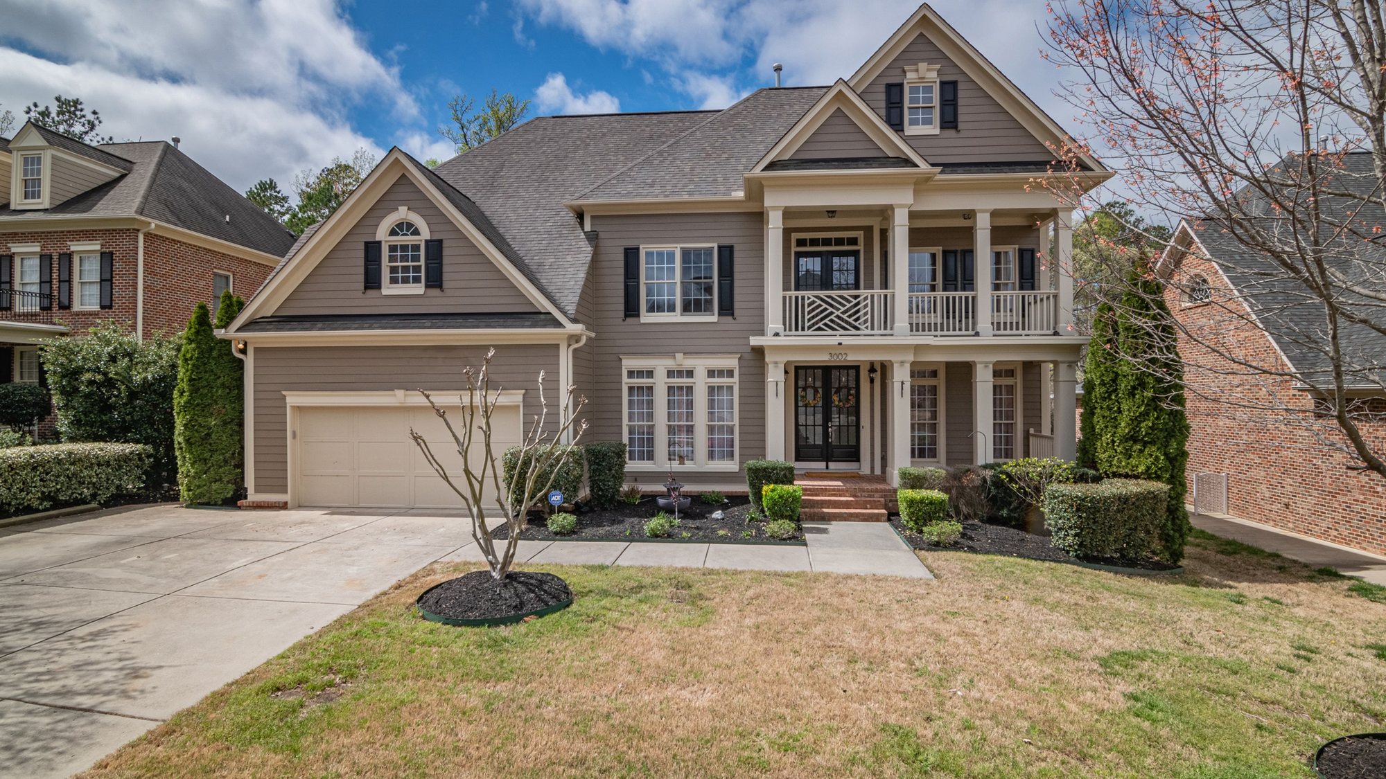 A tan two-story house with a columned porch