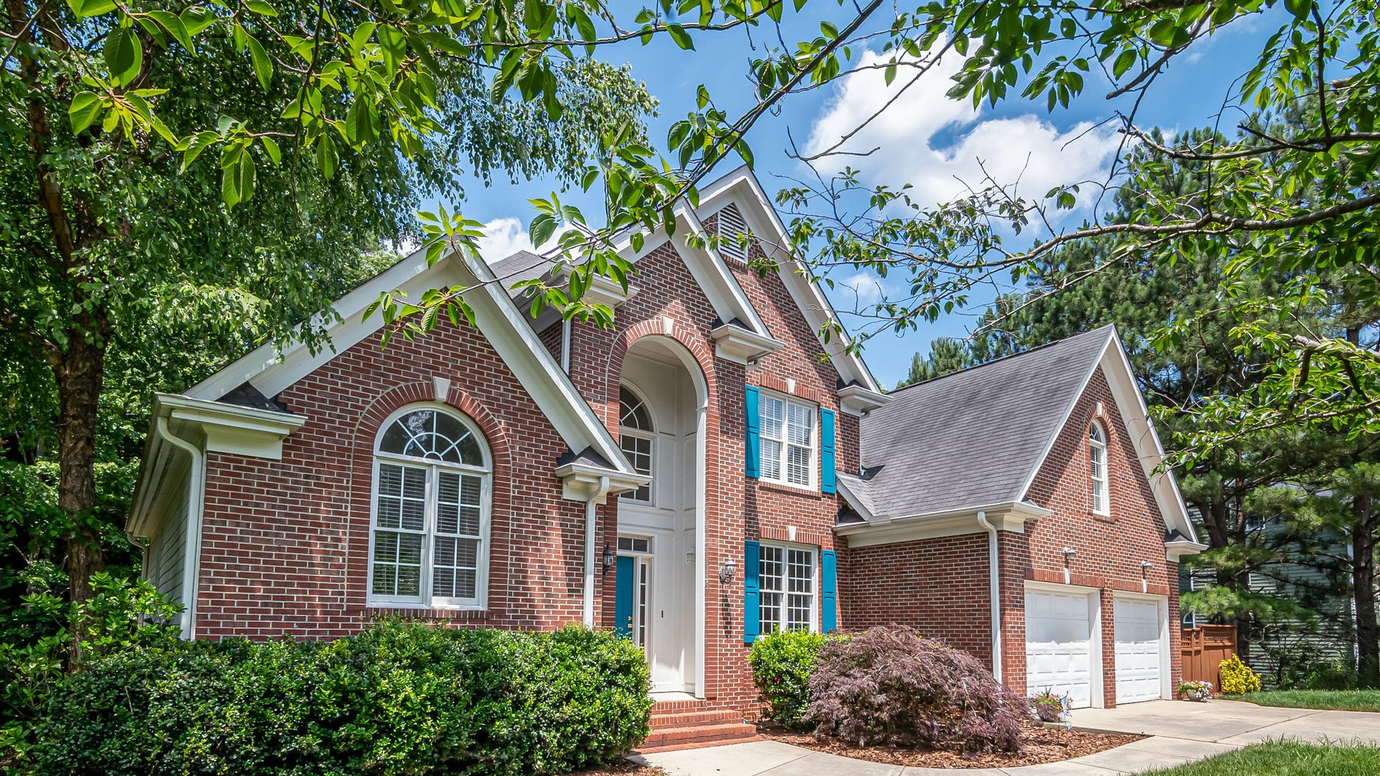 A cream two-story house with a brown metal roof