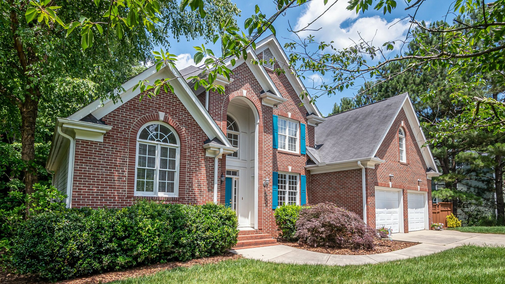 A red brick two-story house with a green lawn